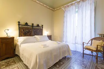 a bedroom with a bed and a chair and a window at B&B Porta Carolina in Palermo