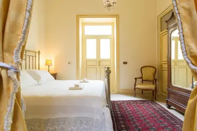 a bedroom with a bed and a chair and a window at B&B Porta Carolina in Palermo