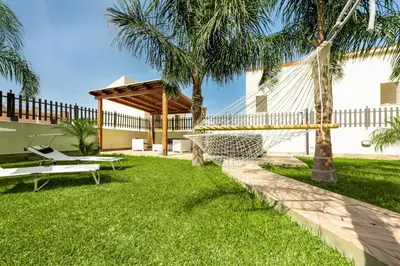 a hammock in a yard with palm trees at Samira in San Vito lo Capo