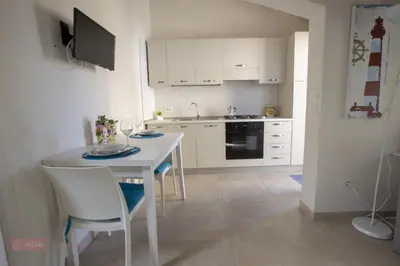 a kitchen with a white table and white cabinets at Le Gemme di Sicilia Apartments in Castellammare del Golfo