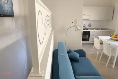 a living room with a blue couch and a kitchen at Le Gemme di Sicilia Apartments in Castellammare del Golfo