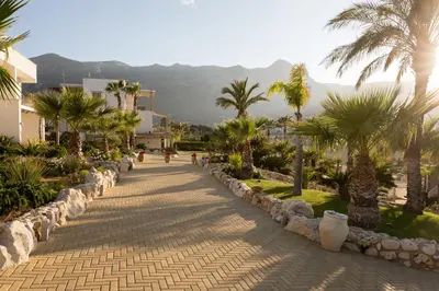 a cobblestone street with palm trees in a resort at La Blanca Resort & Spa in Castellammare del Golfo