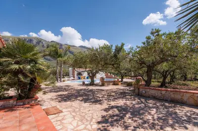 a bedroom with a white bed and a chair at Villa Le Sterlizie in Castellammare del Golfo