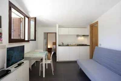 a room with a bed and a table and a kitchen at Villetta Blusanvito in San Vito lo Capo