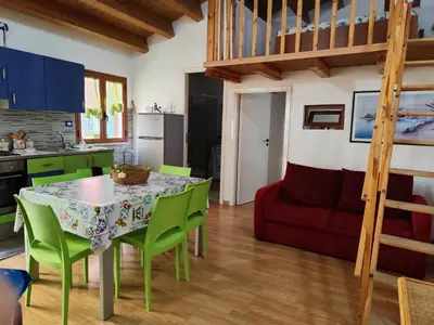 a kitchen and dining room with a table and green chairs at La Perla sul Golfo in Castellammare del Golfo
