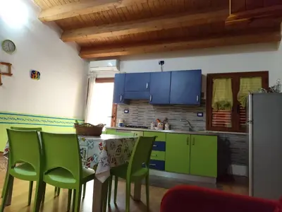 a kitchen with green cabinets and a table with green chairs at La Perla sul Golfo in Castellammare del Golfo