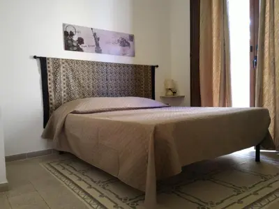 a bedroom with a bed with a headboard and a window at I due Archi in Castellammare del Golfo