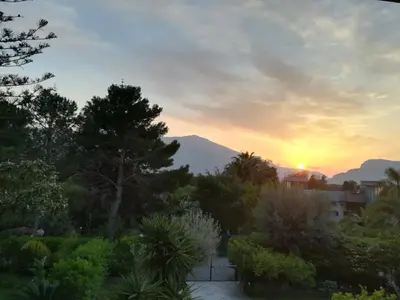 a sunset over a garden with a mountain in the background at Villa Maria in Mondello