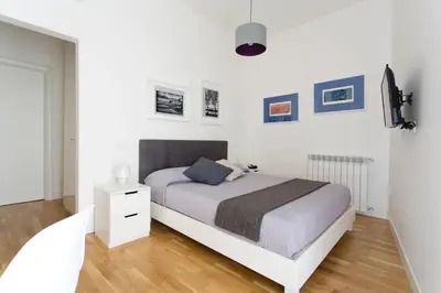 a white bedroom with a white bed and a wooden floor at BB4U Apartments in Palermo