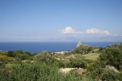 a view of the ocean from a hill with trees at Villa Rossana in Scopello