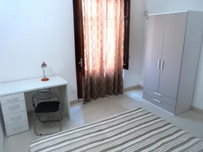 a bedroom with a desk and a chair and a window at Orange House a Castellammare del Golfo in Castellammare del Golfo