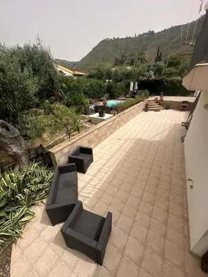 a patio with two black benches and a pool at Villa Giorgia in Cefalù