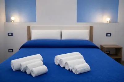 a blue bed with four folded towels on it at A Mare Appartamenti in Castellammare del Golfo