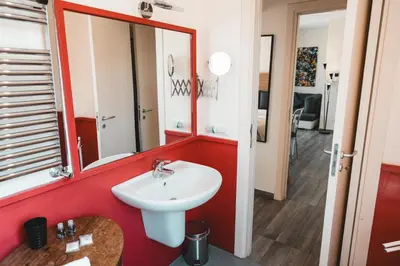 a bathroom with a white sink and a red wall at Attico 261 - Penthouse in Palermo