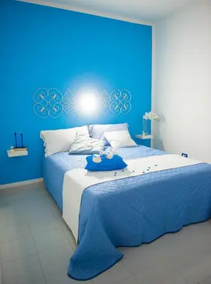a blue bedroom with a large bed with a blue wall at Blue Suite in Castellammare del Golfo