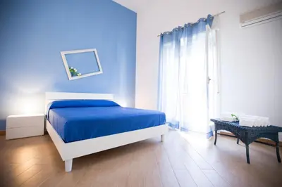 a blue bedroom with a bed and a window at Appartamento Nettuno in Castellammare del Golfo