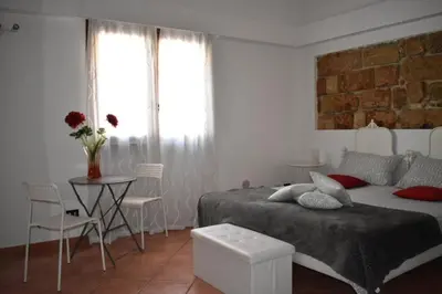 a bedroom with a bed and a table and a window at Alma Nua in Terrasini