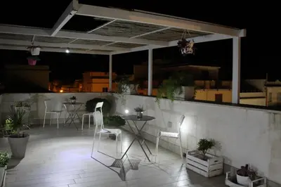 a rooftop patio at night with chairs and tables at Alma Nua in Terrasini