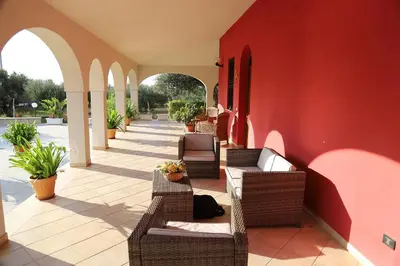 a patio with wicker chairs and a red wall at Lucy's cottage in Cinisi