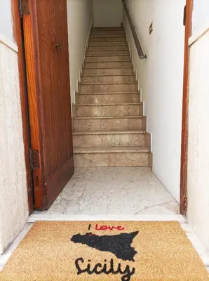 a stairway with a welcome mat in front of a door at Carpe Diem Apartments in Castellammare del Golfo