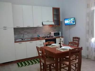 a kitchen with a wooden table and a kitchen with white cabinets at Carpe Diem Apartments in Castellammare del Golfo