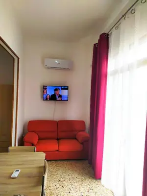 a living room with a red couch and a tv at Carpe Diem Apartments in Castellammare del Golfo