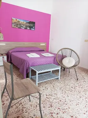 a bedroom with a purple bed and two chairs at Carpe Diem Apartments in Castellammare del Golfo