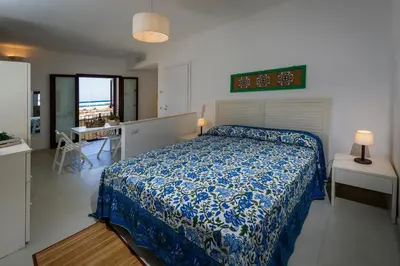 a bedroom with a bed with a blue comforter at N'amuri Residence in Castellammare del Golfo