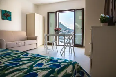 a bedroom with a bed and a table with a view at N'amuri Residence in Castellammare del Golfo