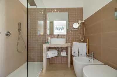 a bathroom with a sink and a toilet and a mirror at Hotel Soffio D'Estate in San Vito lo Capo