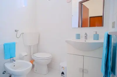 a white bathroom with a toilet and a sink at La Casa delle Ginestre in Alcamo Marina