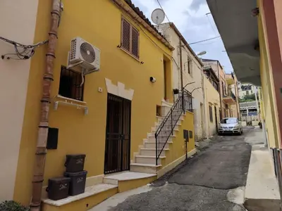 a yellow building with stairs on a street at La Marina in Castellammare del Golfo