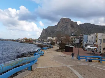 a person standing near the water with a mountain in the background at La Palma San Francesco in Sferracavallo