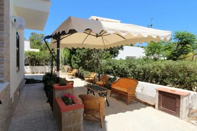 a patio with a table and chairs and an umbrella at B&B Villa Bea in San Vito lo Capo