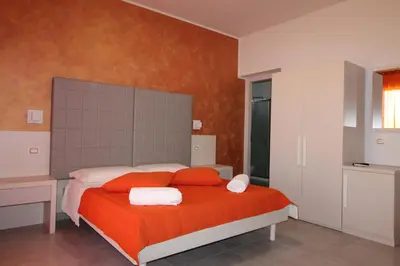 a bedroom with a bed with orange sheets and red pillows at B&B Villa Bea in San Vito lo Capo