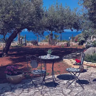 a table and two chairs sitting under a tree at Villa Cala Bianca in Castellammare del Golfo