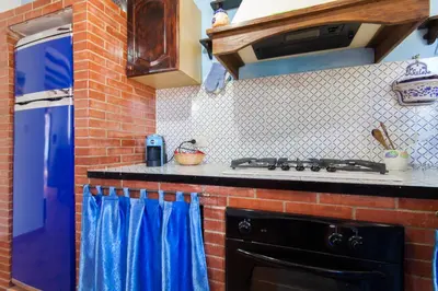 a kitchen with a black stove and blue curtains at Villa Cala Bianca in Castellammare del Golfo