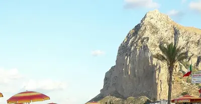 a mountain with a palm tree in front of it at Il Bambu' in San Vito lo Capo