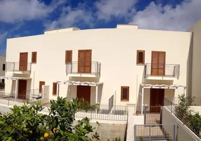 a large white building with brown shuttered windows at Il Bambu' in San Vito lo Capo