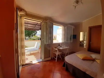 a bedroom with a bed and a view of a patio at Le Casette in Santa Flavia