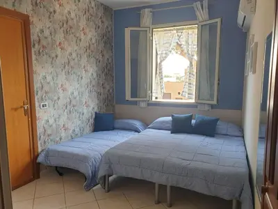 two beds in a bedroom with a window at Le Casette in Santa Flavia