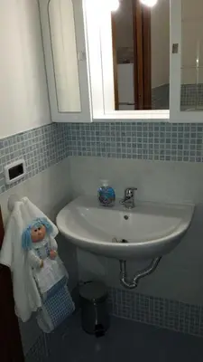 a bathroom sink with a doll sitting on a towel at Le Casette in Santa Flavia