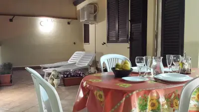 a table with a red table cloth and white chairs at Le Casette in Santa Flavia