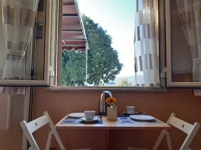 a table with two chairs in front of a window at Le Casette in Santa Flavia