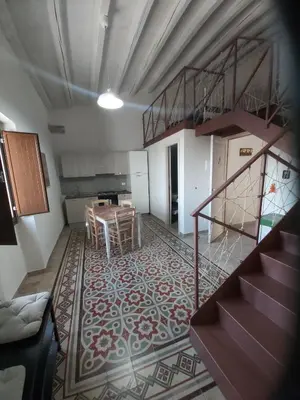 a kitchen and dining room with a table and stairs at Nelle Antiche Mura in Castellammare del Golfo
