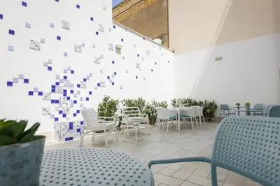 a room with tables and chairs and a wall with squares at B&B Kolors in Castellammare del Golfo