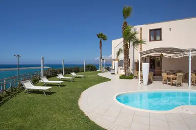 a resort with a swimming pool and tables and chairs at Marina Holiday Hotel & Spa in Balestrate