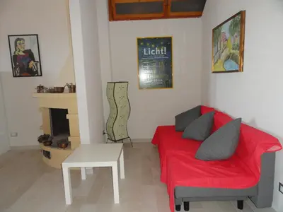a living room with a red couch and a fireplace at Piccola Baia in Scopello