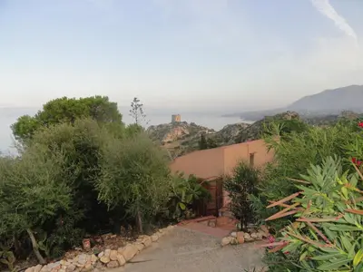 a path leading to a house with a mountain in the background at Piccola Baia in Scopello