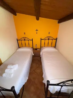 two beds in a room with a yellow wall at Villa delle Cecilie in Partinico